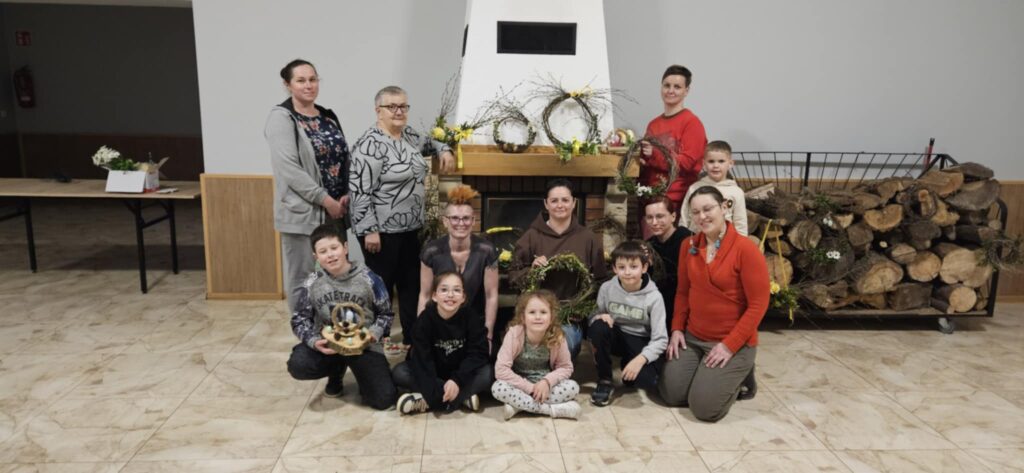 Grupa osób stoi na tle kominka