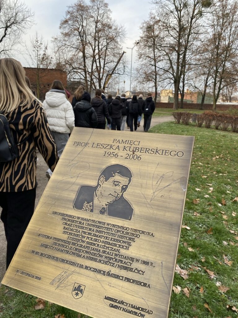 Murowana tablica pamiątkowa, z wygrawerowanym opisem i portretem bohatera