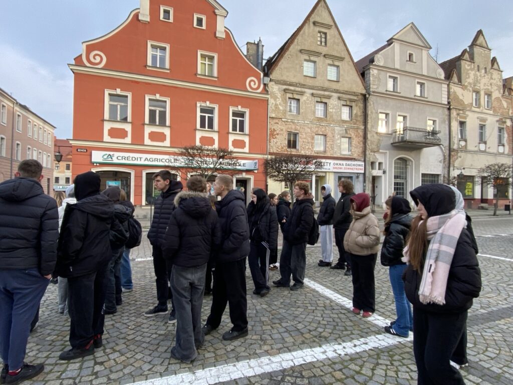 grupa młodzieży na tle kamieniczek na rynku Namysłowa