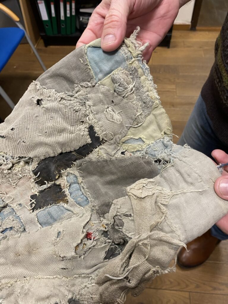 oryginalne spodnie, bardzo zmniszczone z pasiaków z Auschwitz, na które naszytych jest mnóstwo łatek zakrywających pasiastą bawełnę oryginału. Spodnie są podziurawione i przetarte - zostały przywiezione przez więzioną w Auschwitz mieszkanke Namysłowa. obecnie znajdują sie w zbiorach Izby regionalnej w Namysłowie