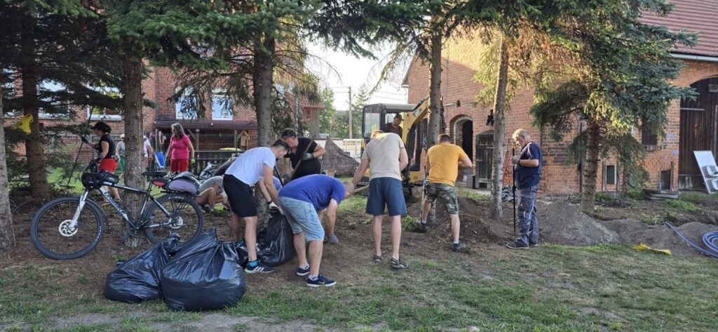 Mieszkańcy Lędzin wspólnie porządkują teren, zbierają odpady i przygotowują przestrzeń wokół budynku przeznaczonego na działalność społeczną.
