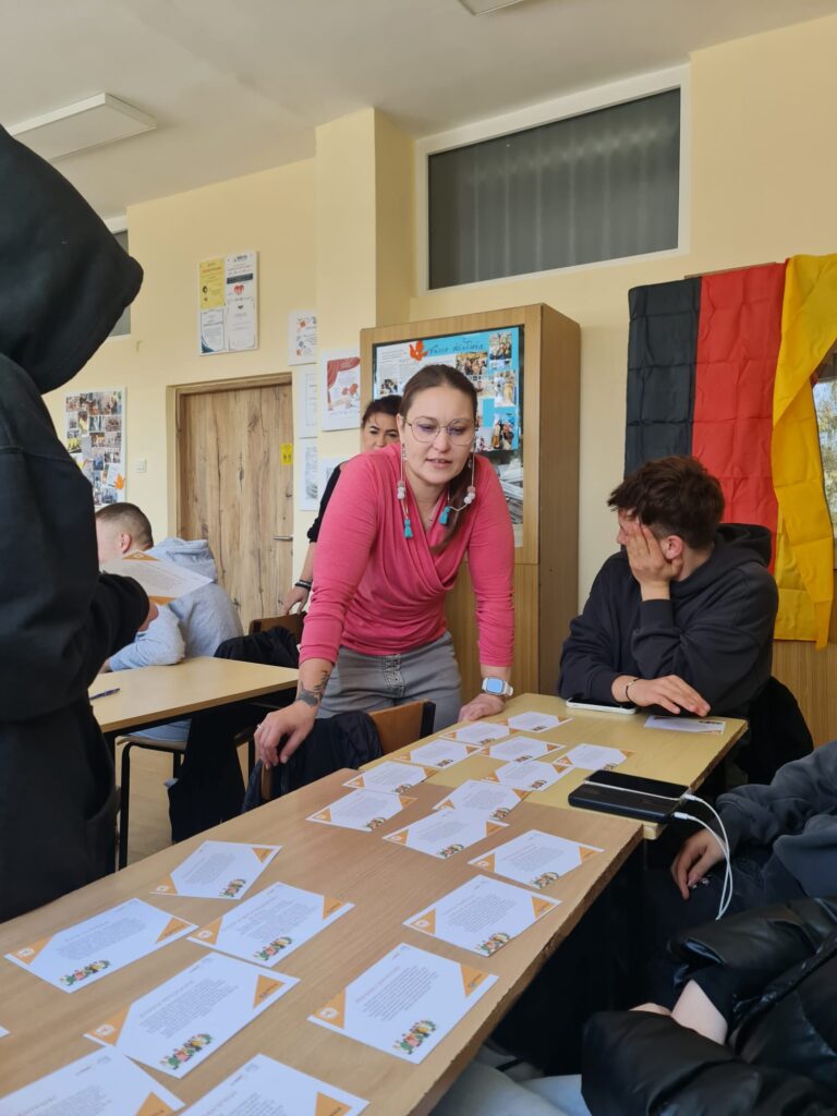grupa młodzieży siexząc przy stoliku qwybiera z kart probelmy, które uważają, ze są najdotkliwsze dla młodzieży. instruktorka się przygląda i zadaje pytania. 